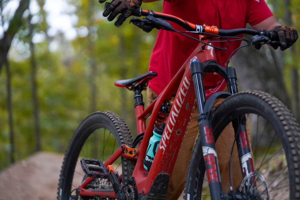 A mountain bike rider walks their red e-mountain bike on the trail.