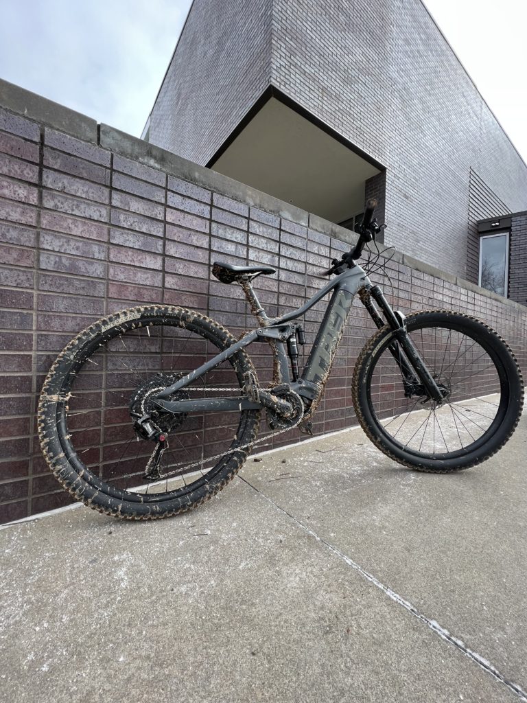 A Trek e-bike leaning against a brick wall.