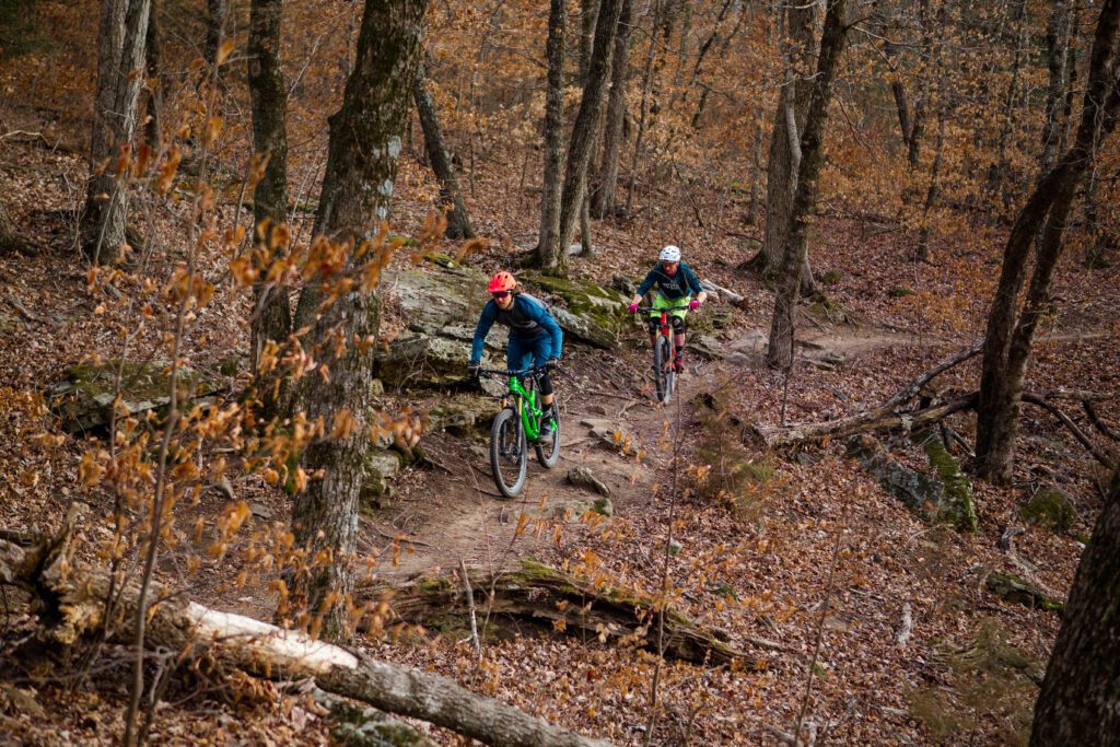 Two riders on the leaf-filled trail