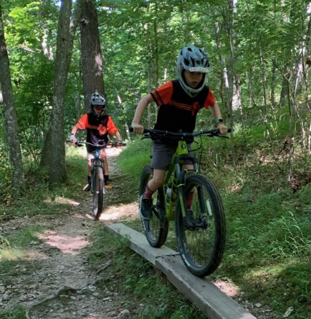 Child riding a mountain bike on a skinny wooden feature