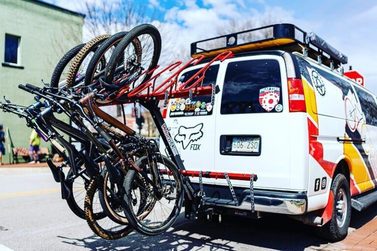OZ Cycling Tours passenger van with four mountain bikes on the rack.