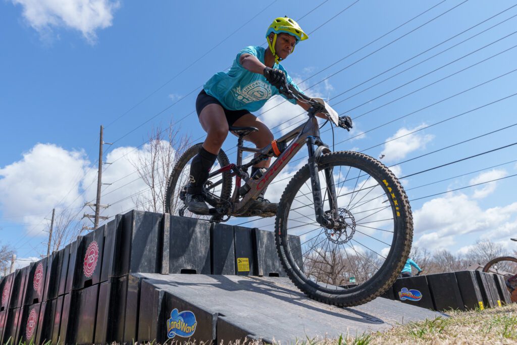 Woman mountain biker doing a drop on her bike and a ramp