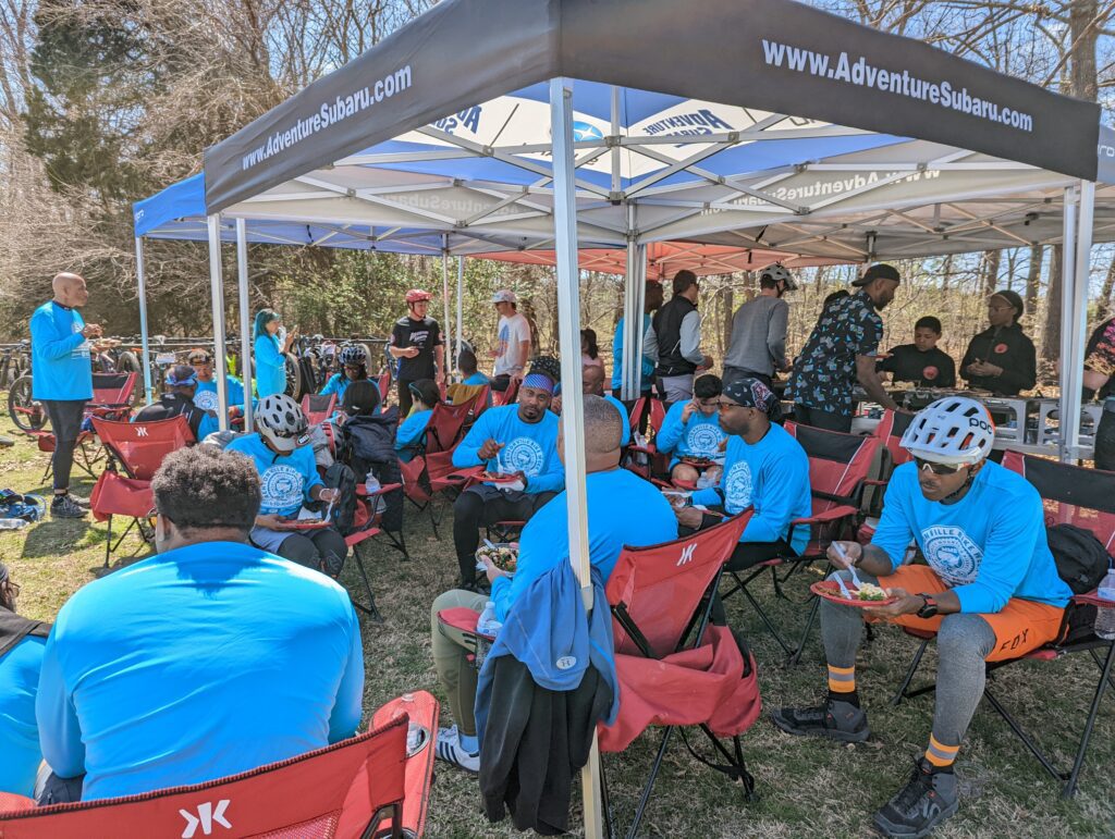 Group takes a rest under a pop-up tent with food.