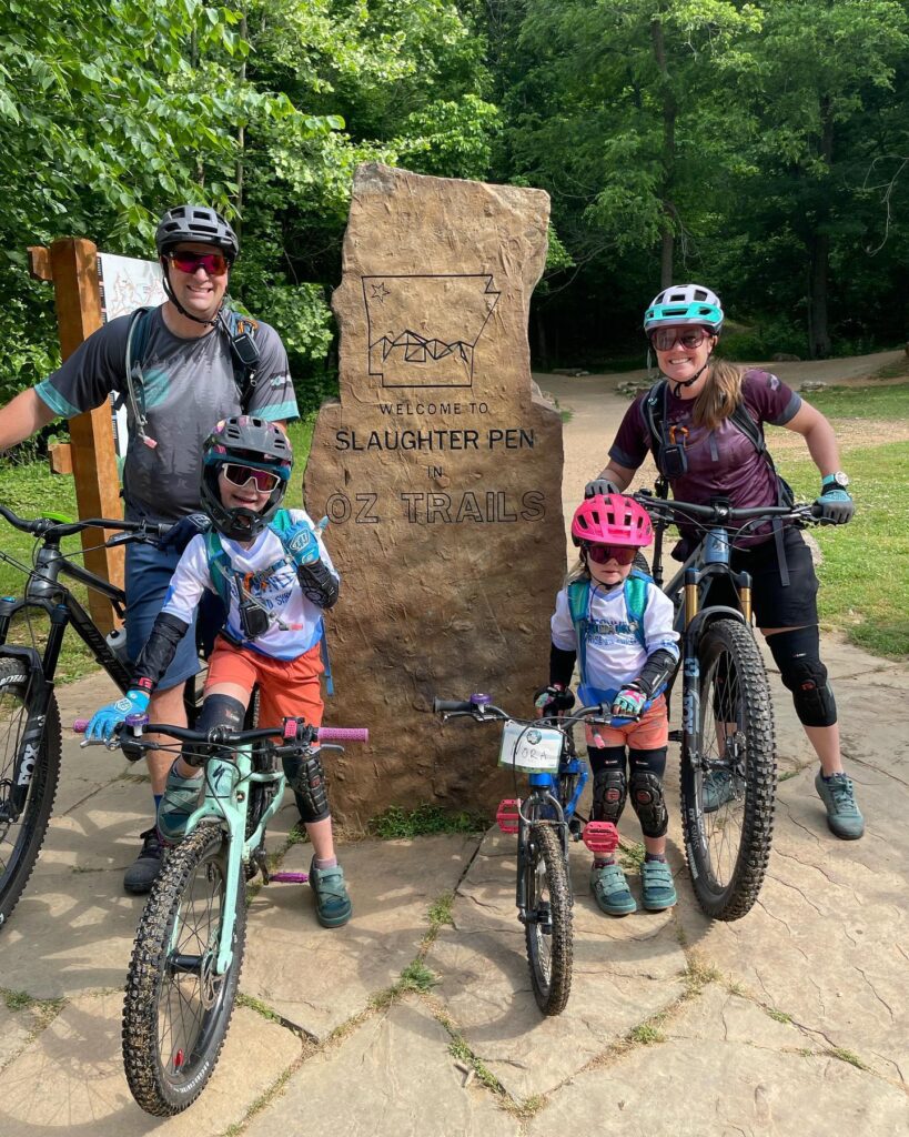 Family on bikes posing by the Slaughter Pen Trails sign