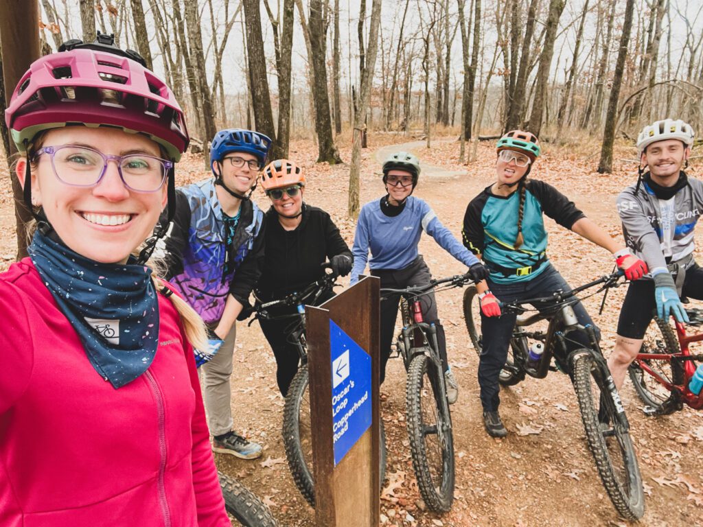 Six mountain bikers stop and smile for a selfie.