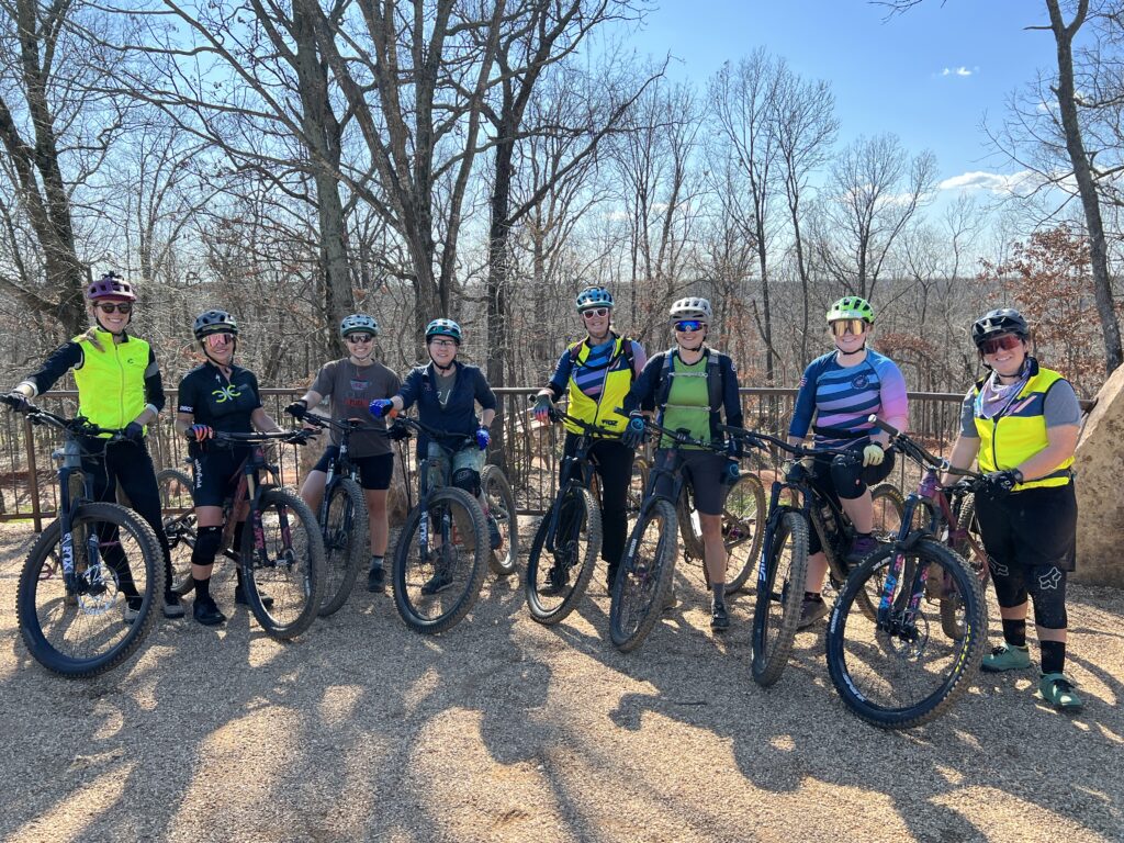 Women mountain bikers pose for a picture standing next to their bikes.