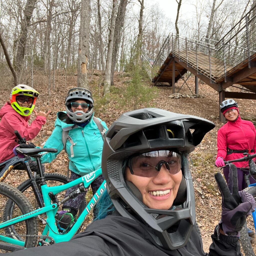 Four ladies smile for a picture while wearing helmets and jackets.