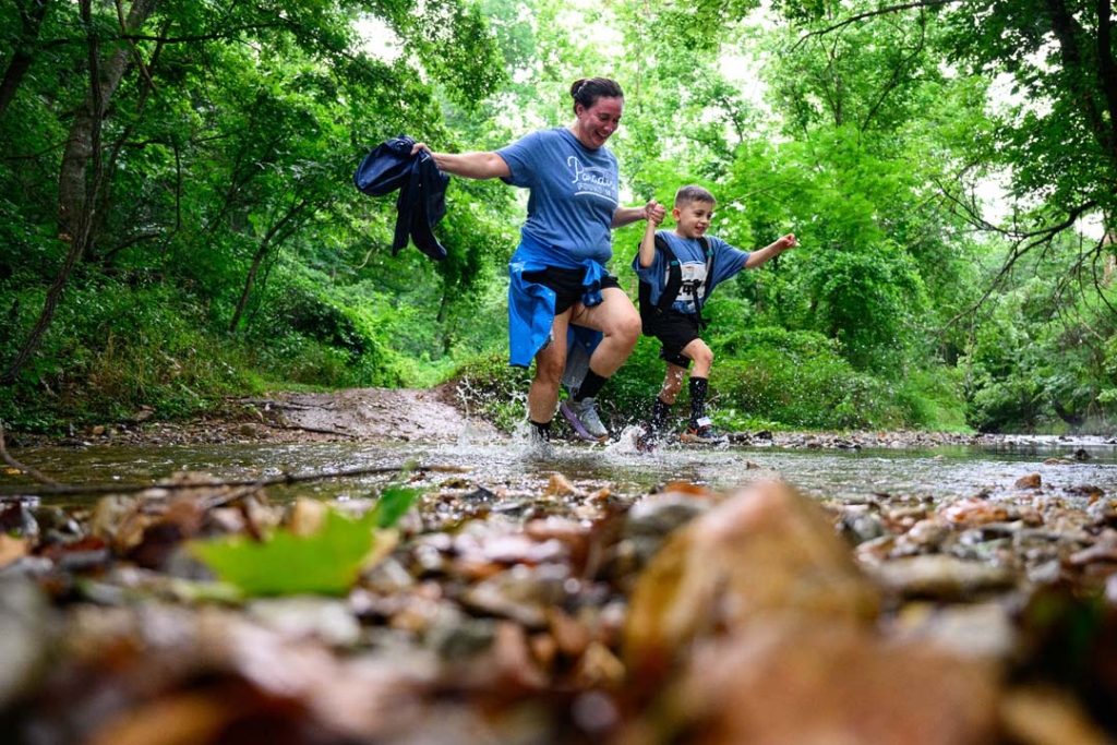 A mom and son crossing the creek while racing the 5k.