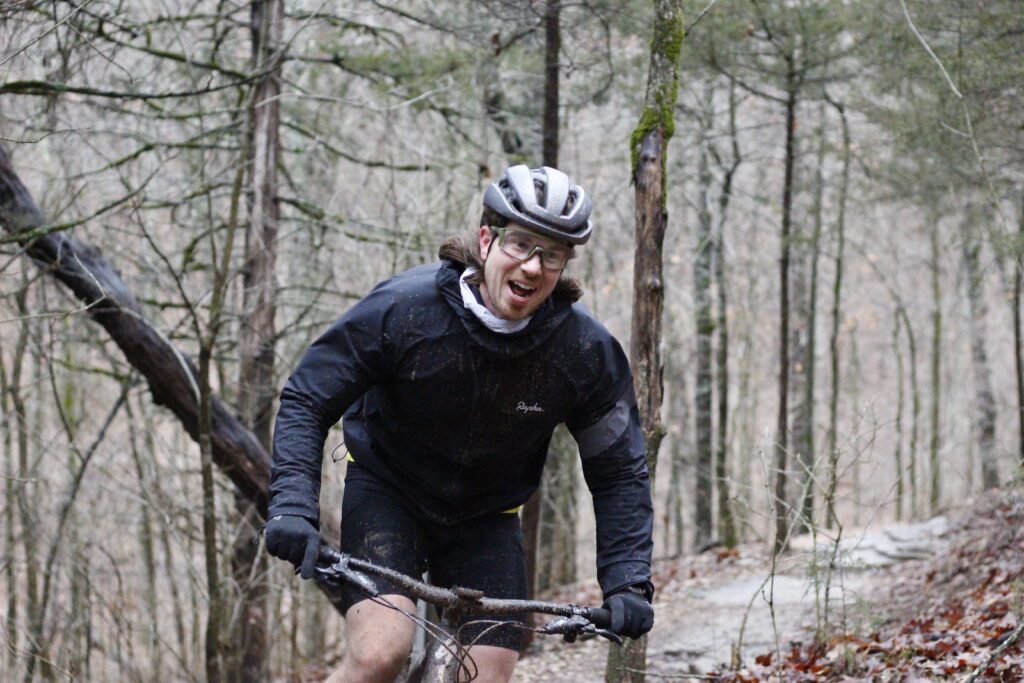 Male rider passing by on the trails smiling.